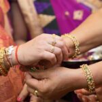 Close-up of women exchanging rings during a traditional Indian wedding ceremony.