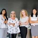 Four professional women standing confidently in an office, symbolizing diversity and teamwork.